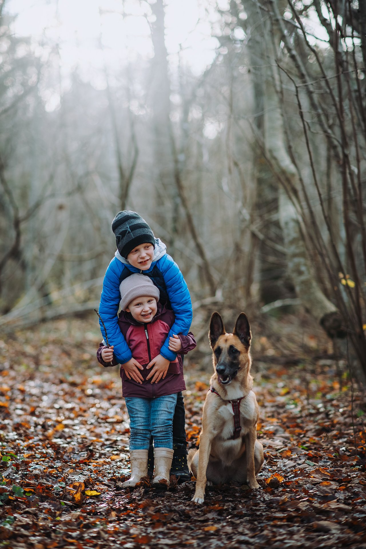 Två barn står tillsammans med familjens hund i skogen