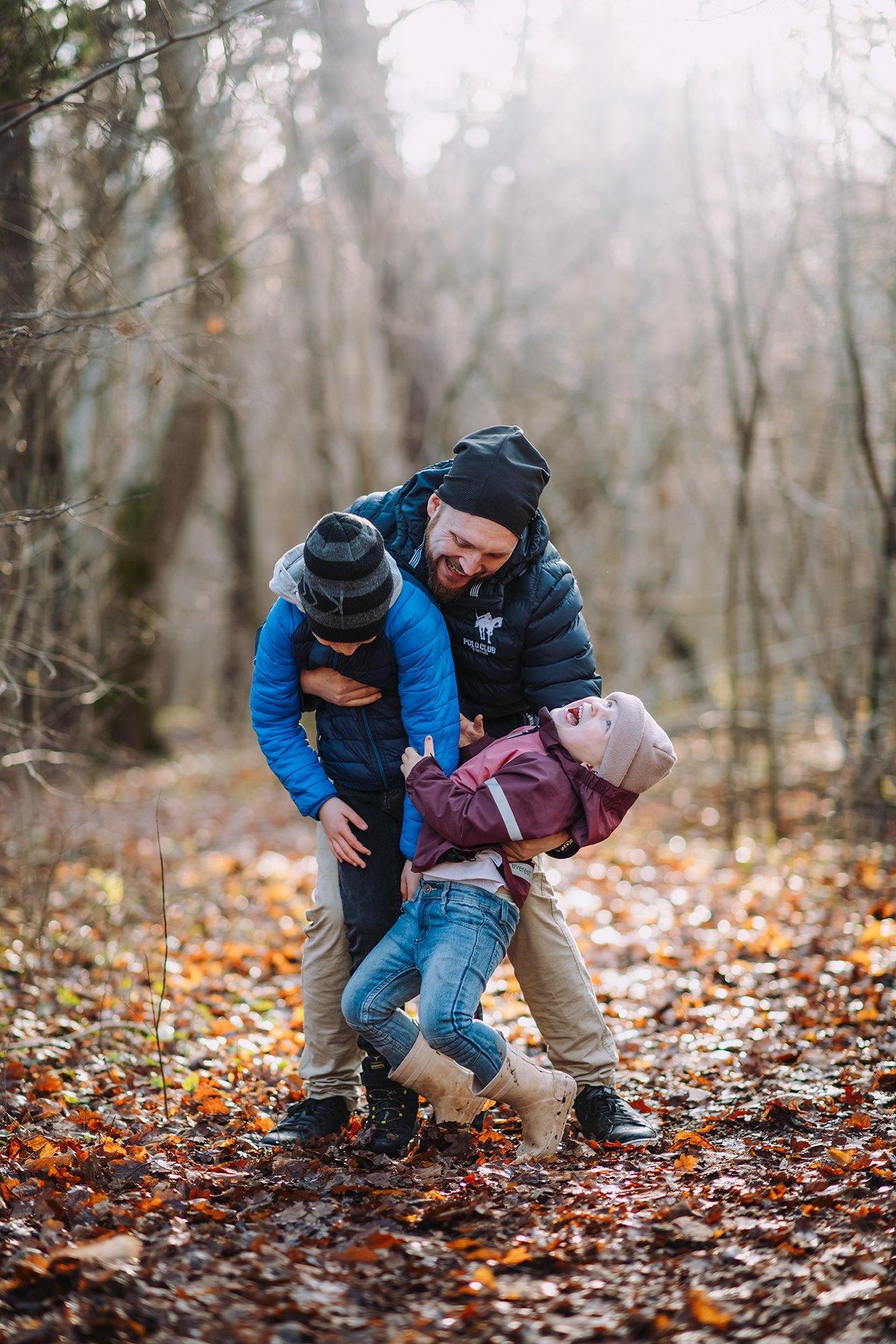 Pappa leker med två barn i skogen på hösten