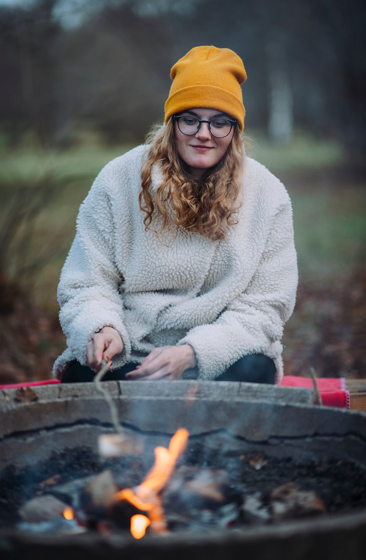 Mamma grillar marshmallows vid eldstad på picknick