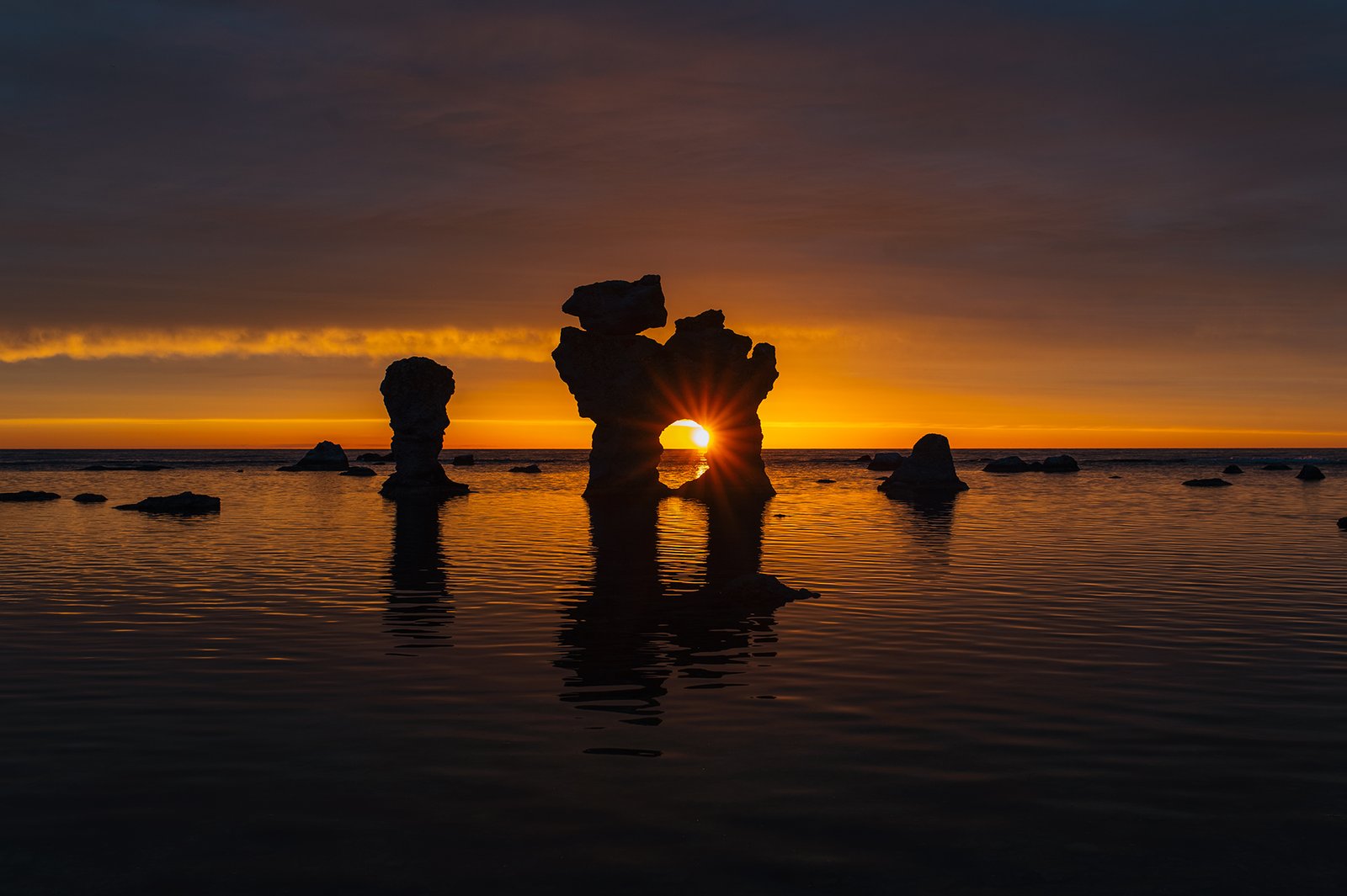 Solnedgång bakom rauken Hunden vid Gamla Hamn på Fårö.