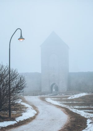 Dalmansporten i Visbys ringmur en dimmig vinterdag med snötäckt gångväg och gatlykta i förgrunden.