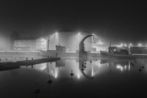 Dimma över Visby hamn en stilla natt med båtar och ljus som speglas i vattnet